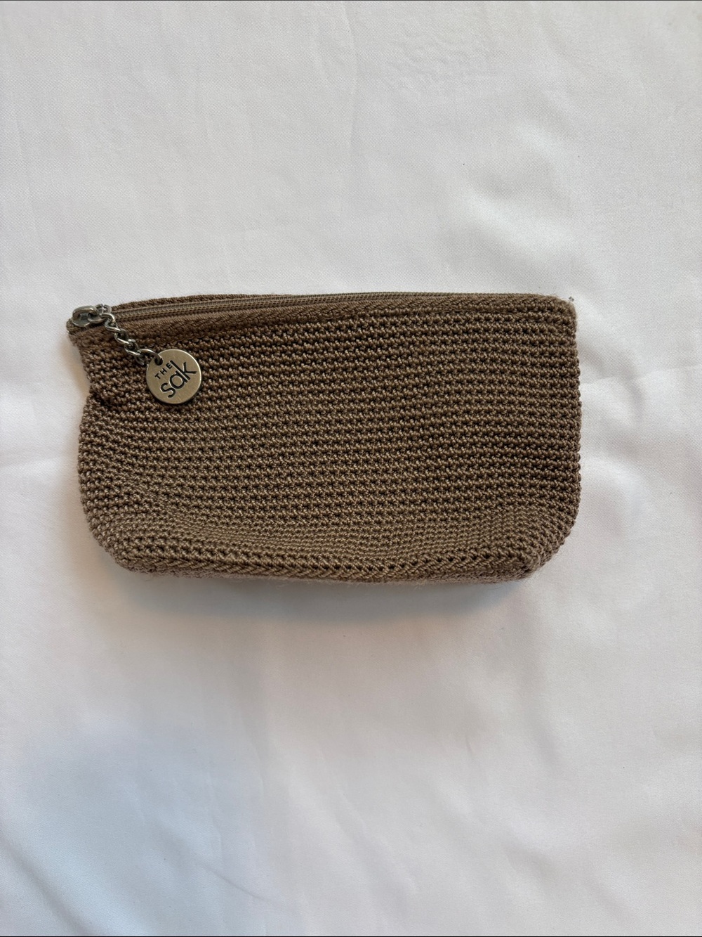The Sak Taupe Crochet Zip Cosmetic Pouch with Branded Charm